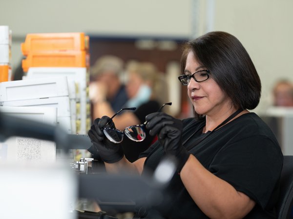 Woman wearing gloves inspecting pair of glasses