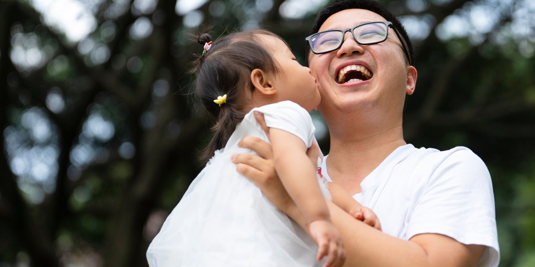 parent with glasses on laughing and holding a baby