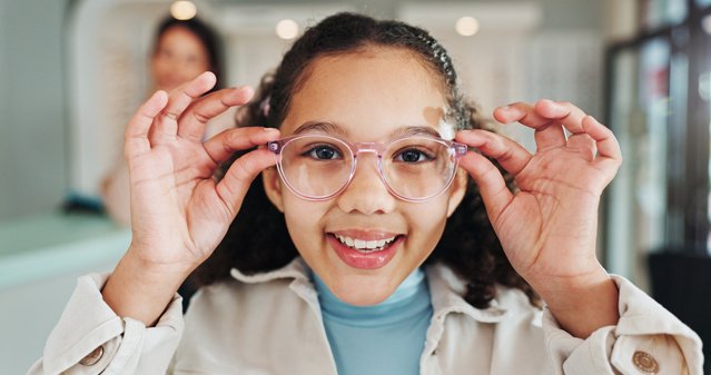 Child trying on eyeglasses and smiling